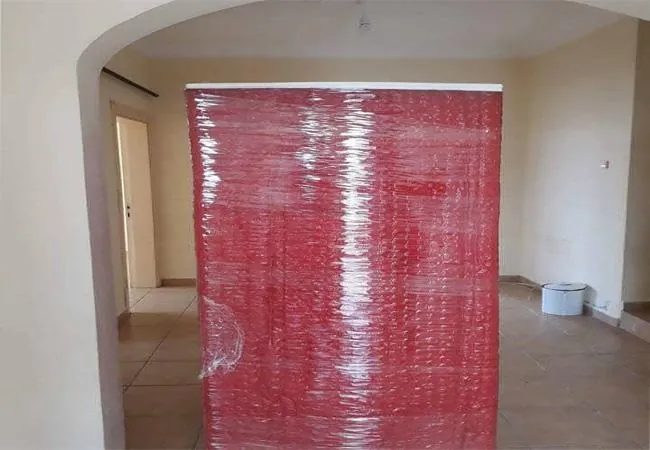 Kırmızı battaniyeyle sarılmış gardırop, boşaltılmış dairenin salonunda