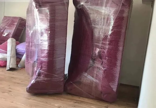 Streçlenmiş koltuklar ve rulo hâlinde sarılmış halı, taşınmaya hazır