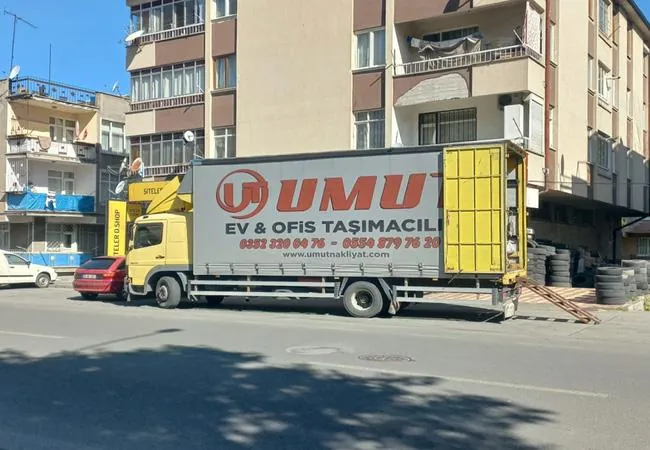 "Umut Ev & Ofis Taşımacılık" yazılı kamyon, apartman önünde