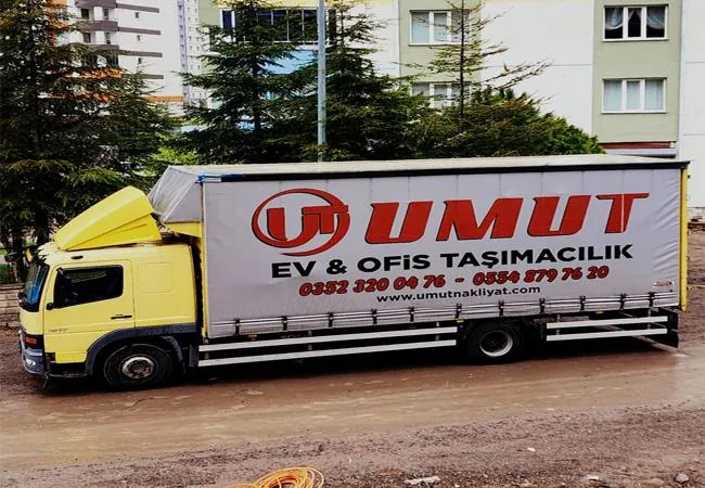 "Umut Ev & Ofis Taşımacılık" yazılı tenteli kamyon, site önünde
