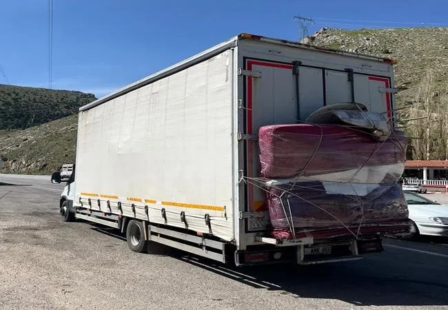 Tenteli kamyonun arkasına yüklenmiş, battaniyeye sarılı eşyalar